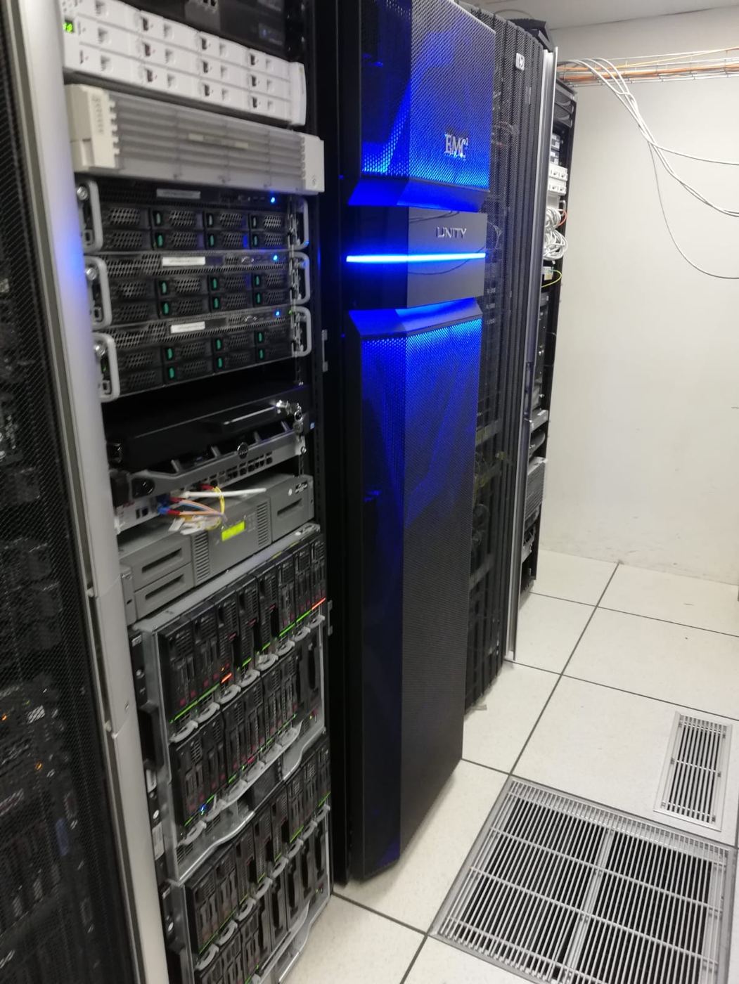 Data centre aisle with server racks and storage array on a raised floor