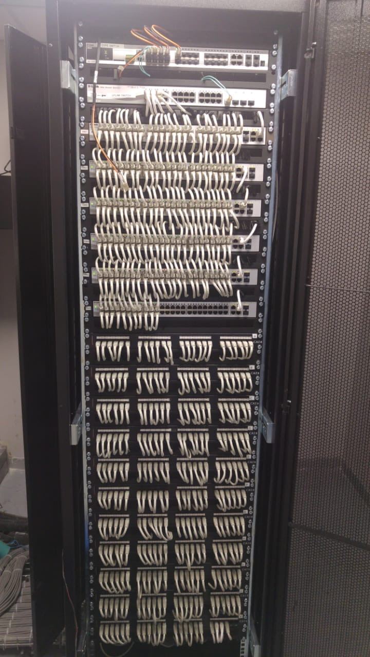 Full-height network rack with eight switches and twelve patch panels, every patch lead dressed